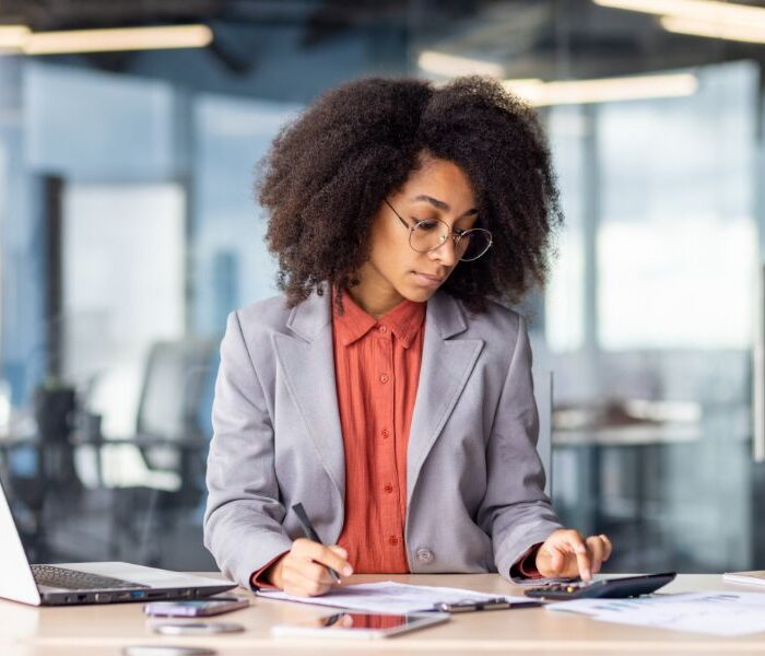 HR professional calculating hiring cost in Aruba at office desk with documents and laptop
