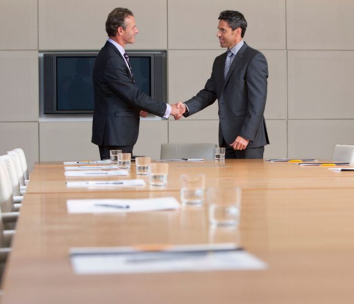 Headhunting services Aruba — executives shaking hands in a boardroom after a leadership placement