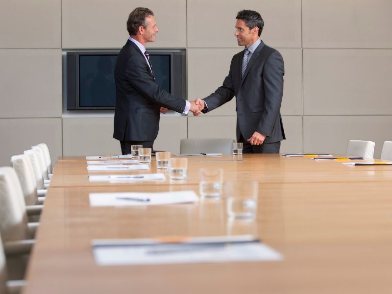 Headhunting services Aruba — executives shaking hands in a boardroom after a leadership placement