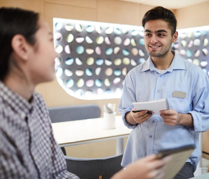 Retail employee with a name badge helping a customer choose eyewear in a modern store